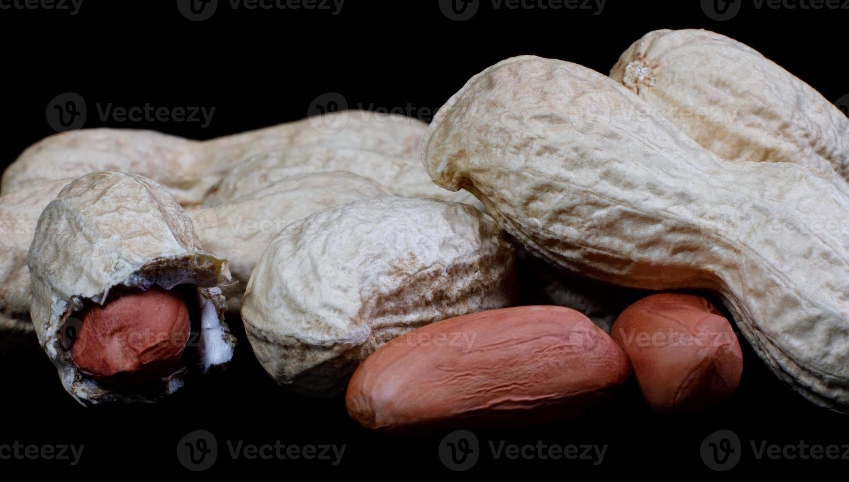 Peanuts in the shell and without it on a black background. photo