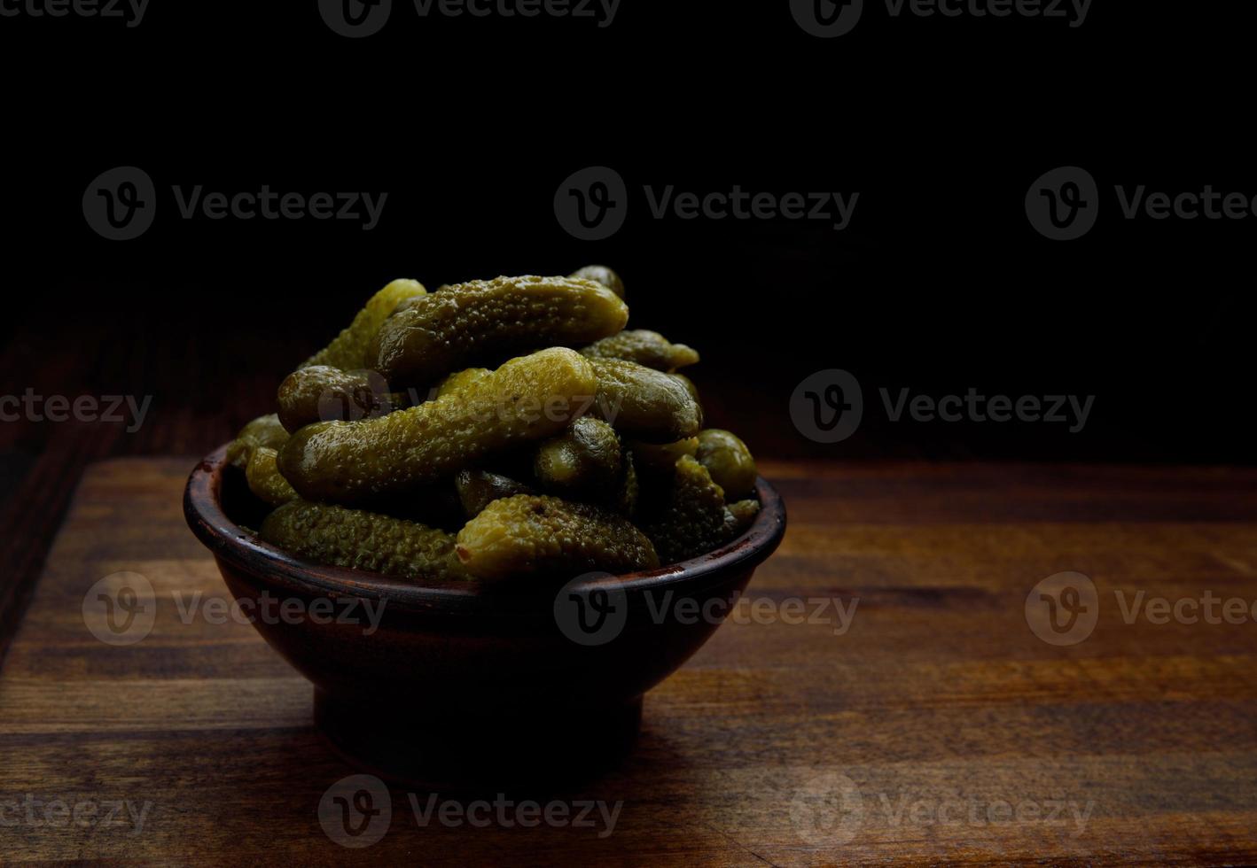 A cup of crispy pickled cucumbers stands on a wooden cutting board. Salted cucumbers. photo