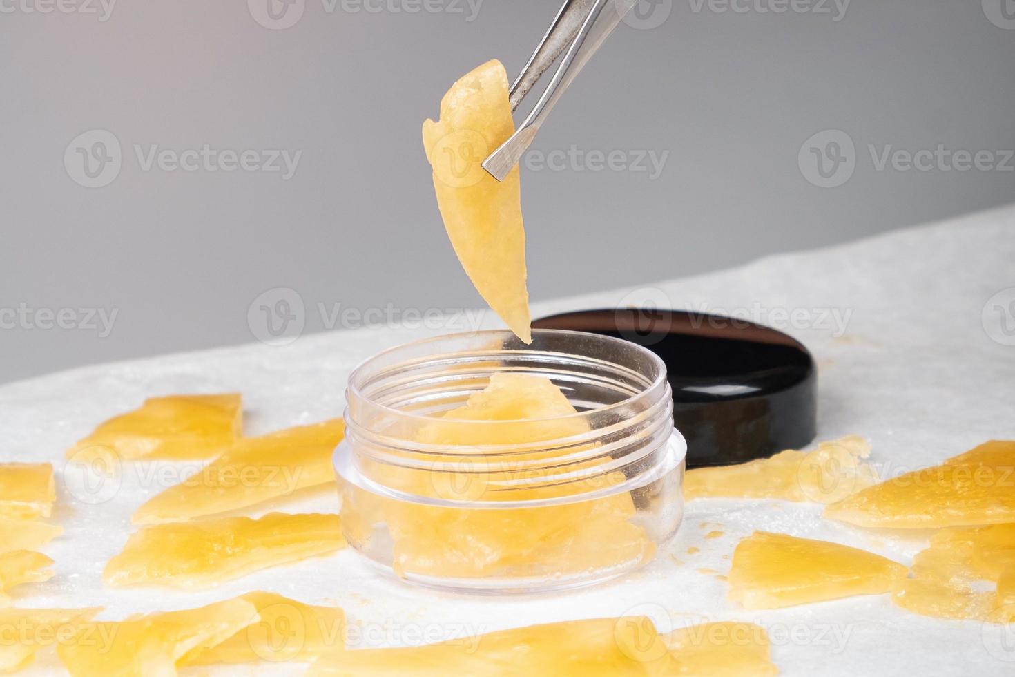 box of golden extract medical marijuana wax and tweezers in hand photo