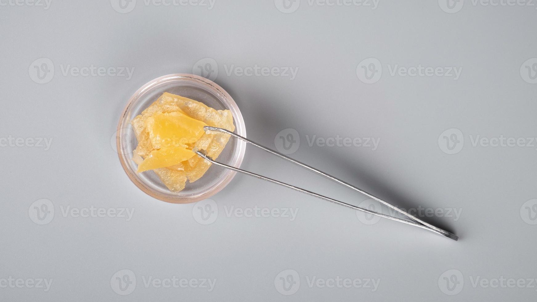 golden smoking cannabis wax and tongs on gray background photo