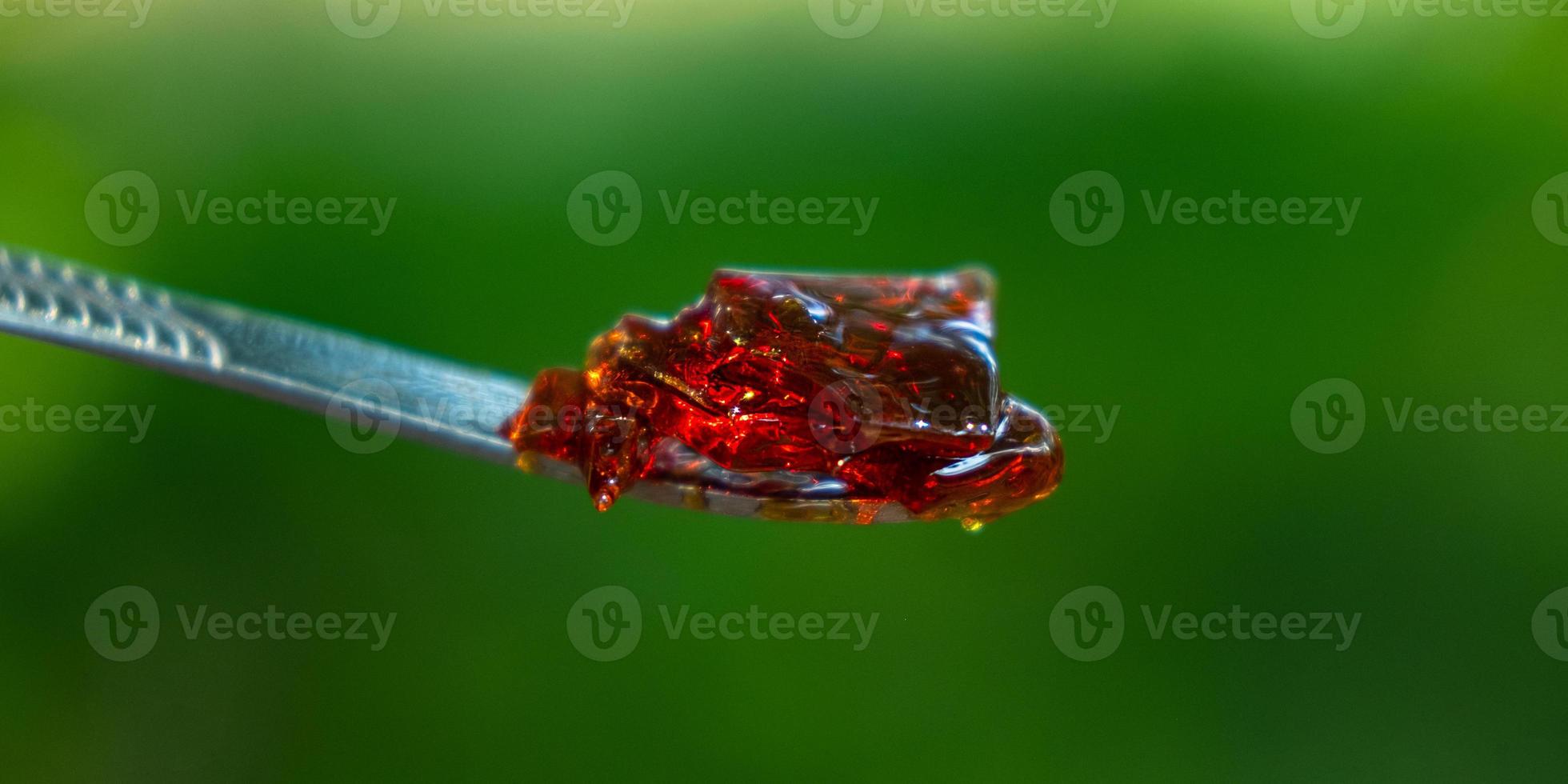amber yellow cannabis wax concentrate dripping from the dabbing tool closeup photo