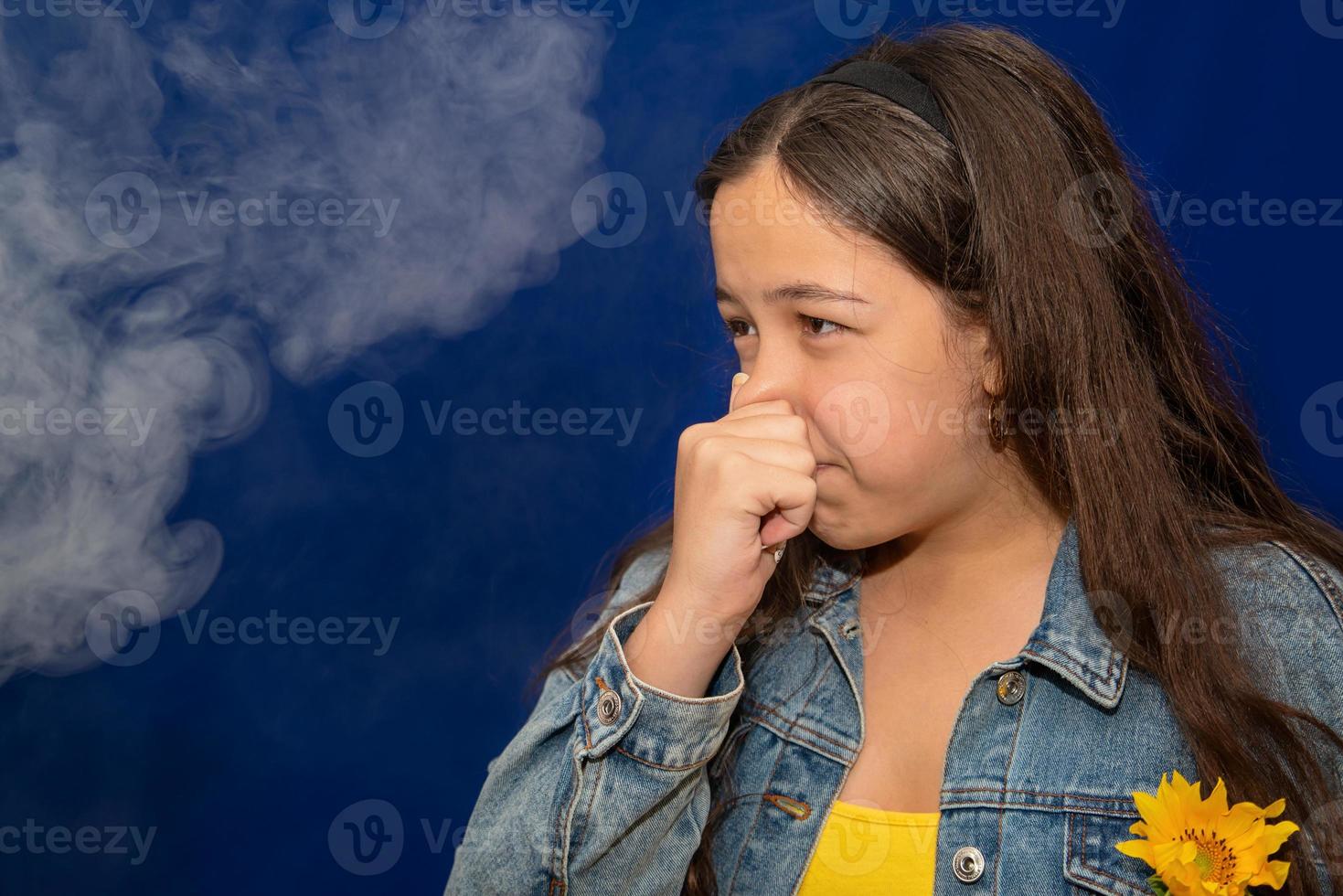 Teen girl pinch her nose because toxic fumes from car,bad smell,air pollution,dust allergies or sinus infection,female teenage rubbing nose suffer from allergic in city,life of urban people. photo