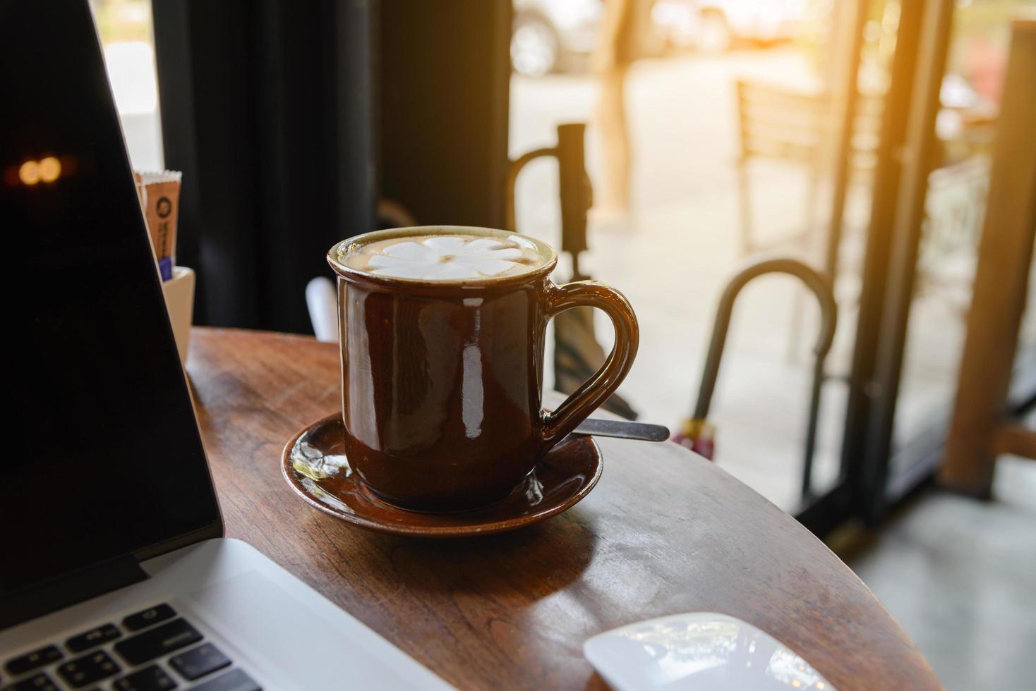 Coffee cup and laptop on wooden table in coffee shop. business concept photo