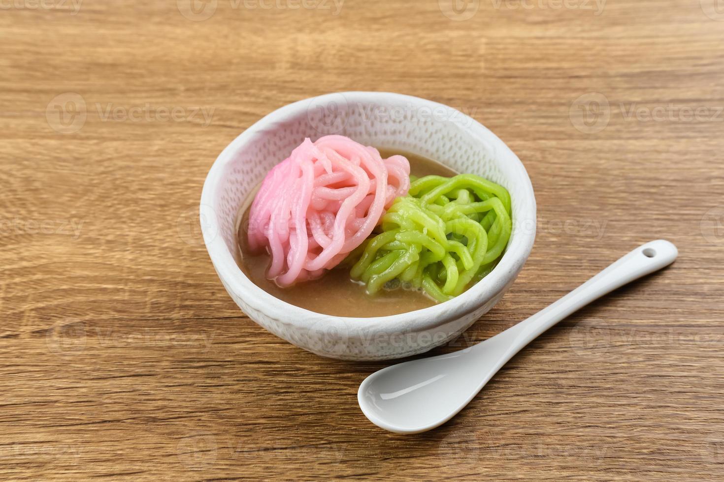 Kue Putu Mayang is traditional Indonesian snack made from rice flour strands curled up into a ball, served with coconut milk and palm sugar. Selected focus. photo