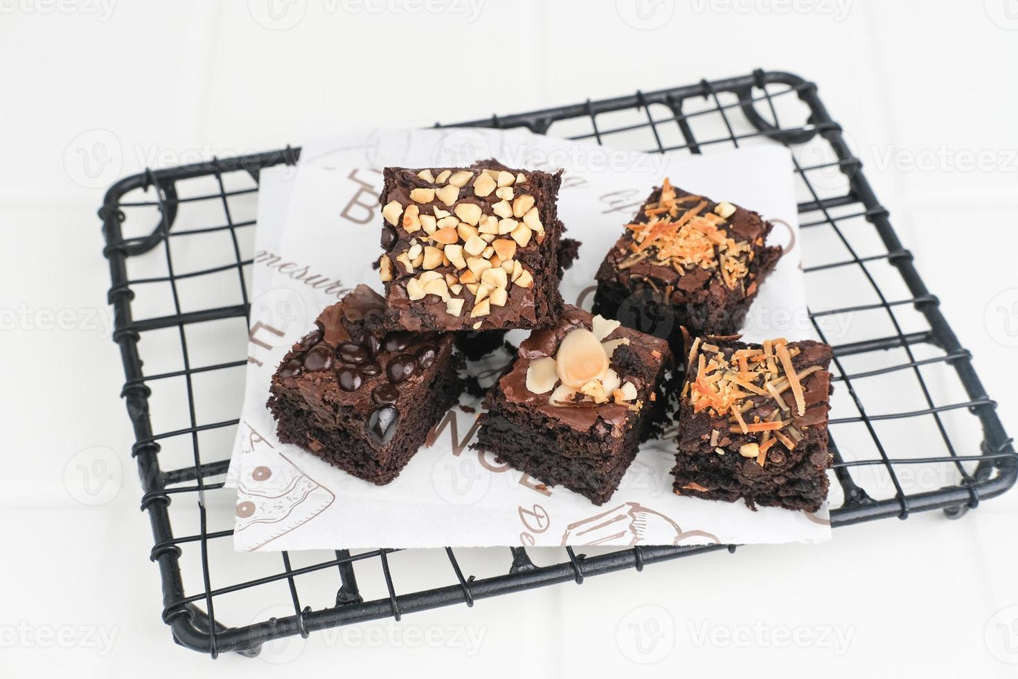 Homemade chocolate fudge brownie with mix topping, close up, served on plate, isolated on white background. Selective focus image. photo