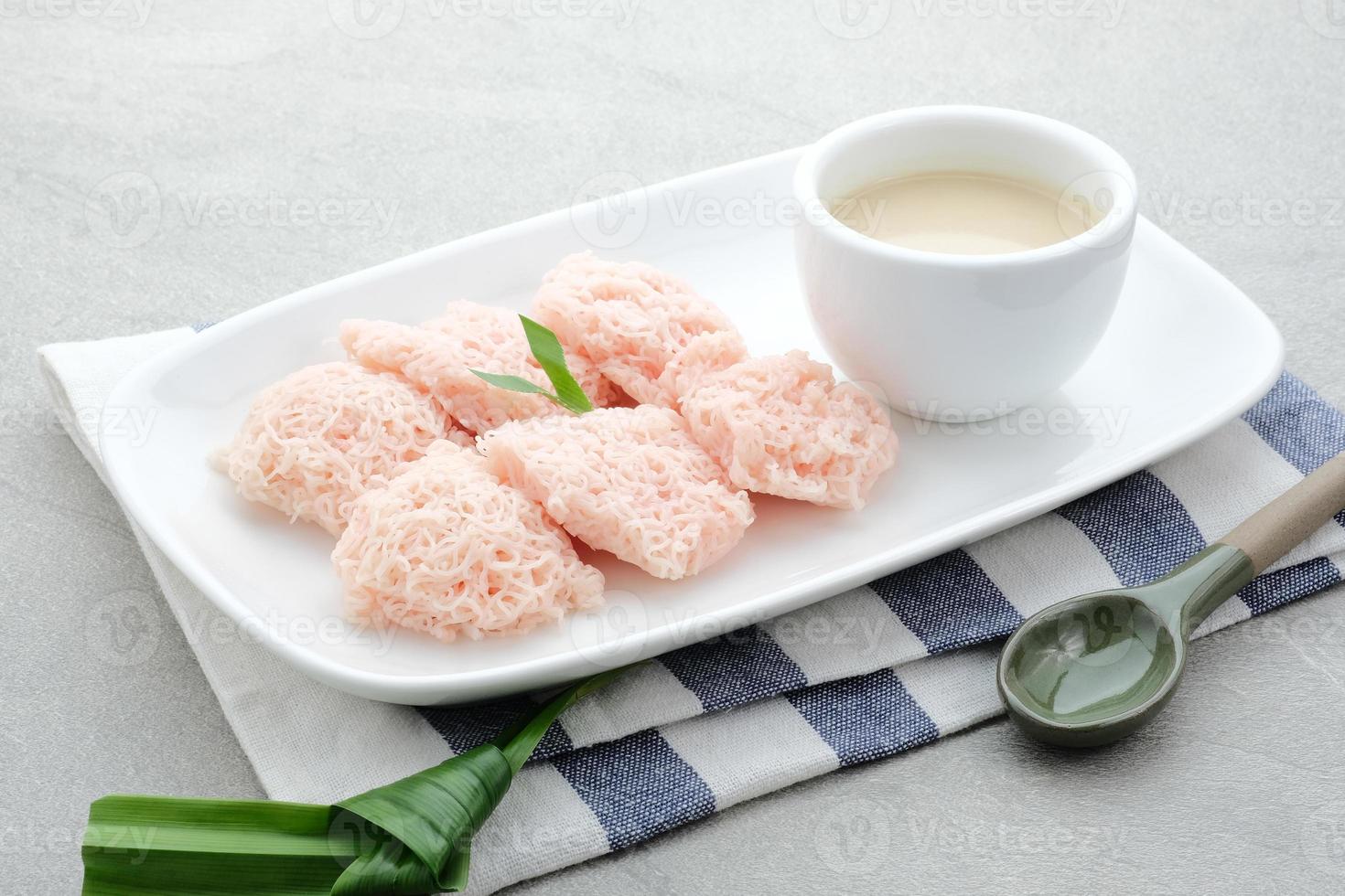 kue putu mayang es un bocadillo tradicional indonesio hecho con hebras de harina de arroz enrolladas en una bola, servida con leche de coco y azúcar de palma. foto