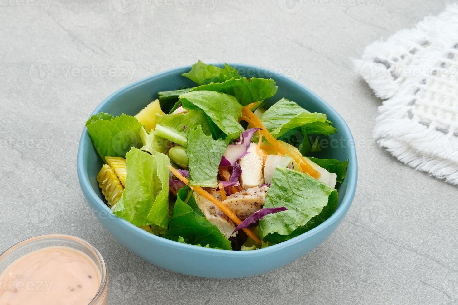Green salad from green leaves mix vegetables, with mayonnaise sauce. Served in tosca bowl on grey table photo