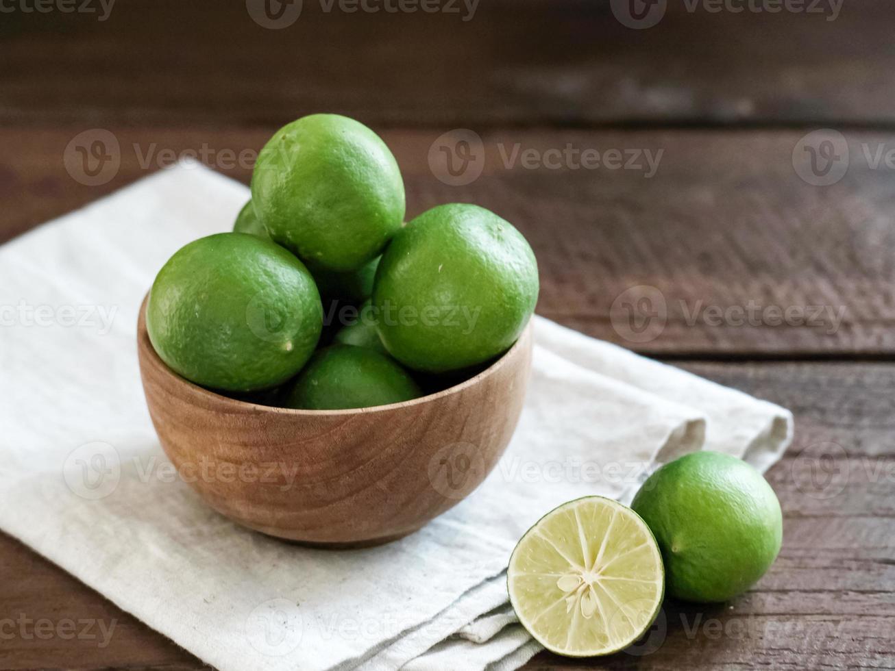 frutas cítricas de lima frescas en un tazón de madera sobre la mesa. foto