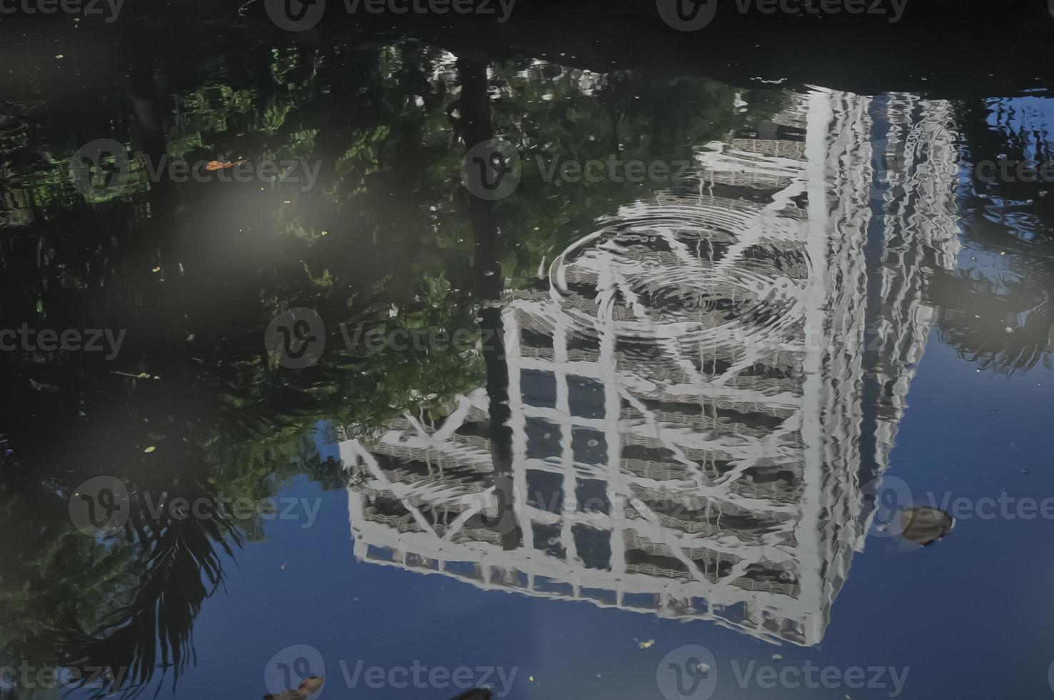 reflection of tall business building in a pond on a sunny day photo