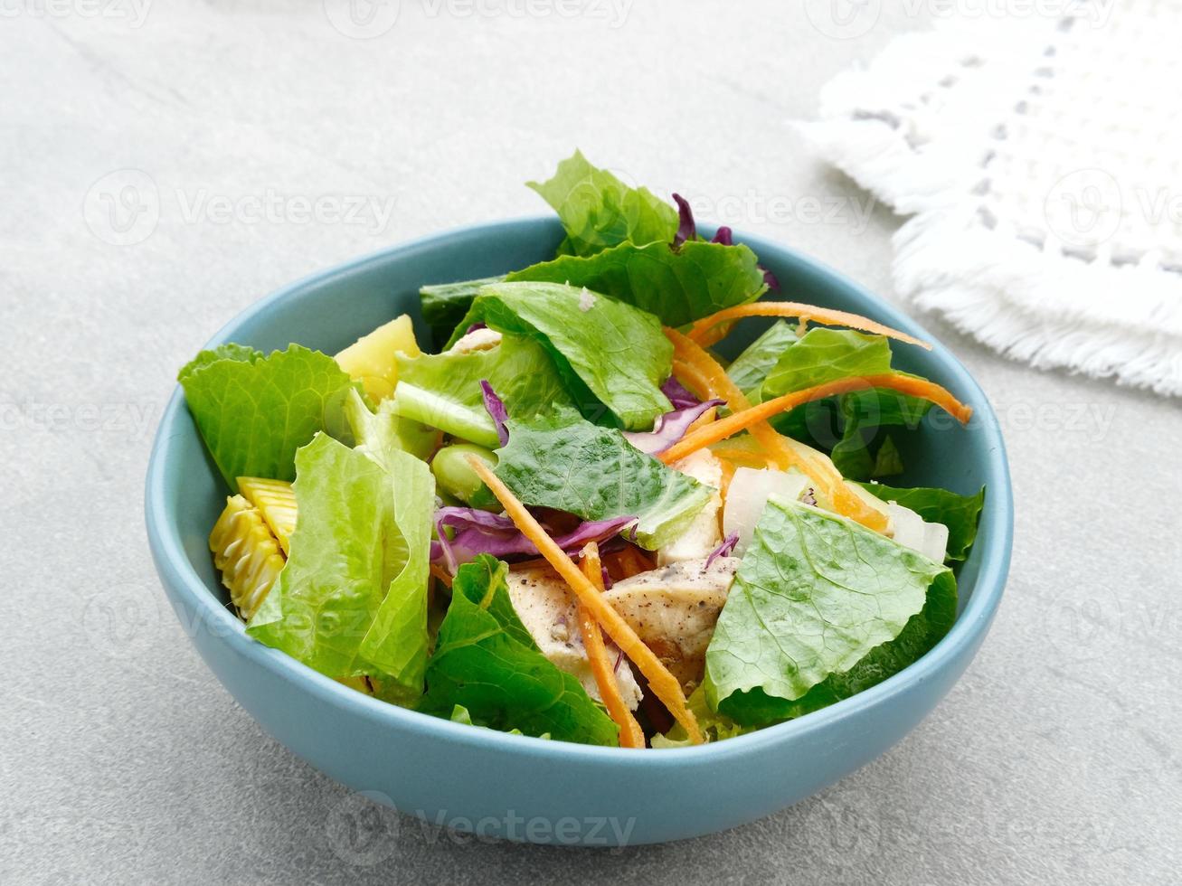 Green salad from green leaves mix vegetables, with mayonnaise sauce. Served in tosca bowl on grey table photo