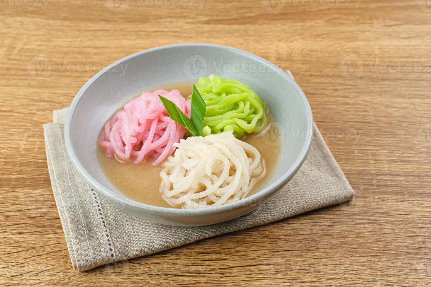 Kue Putu Mayang is traditional Indonesian snack made from rice flour strands curled up into a ball, served with coconut milk and palm sugar. Selected focus. photo