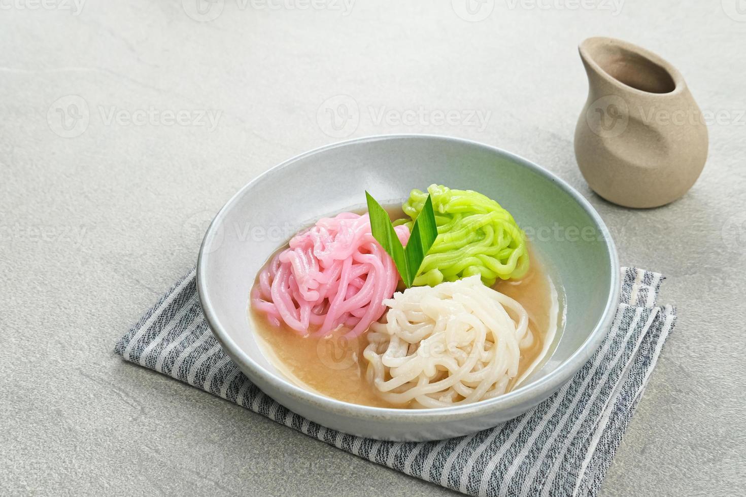 Kue Putu Mayang is traditional Indonesian snack made from rice flour strands curled up into a ball, served with coconut milk and palm sugar. Selected focus. photo