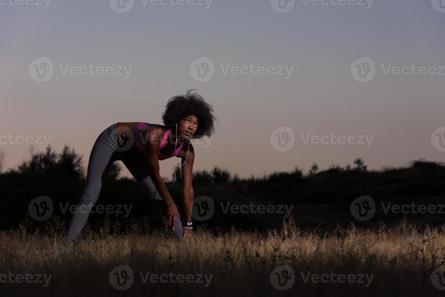 mujer negra está haciendo ejercicio de estiramiento relajándose y calentándose foto