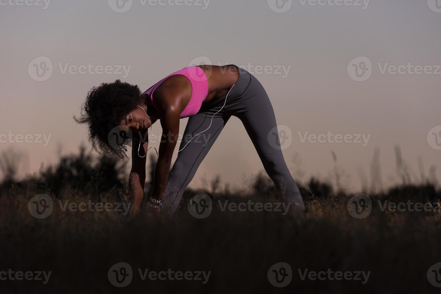 mujer negra está haciendo ejercicio de estiramiento relajándose y calentándose foto
