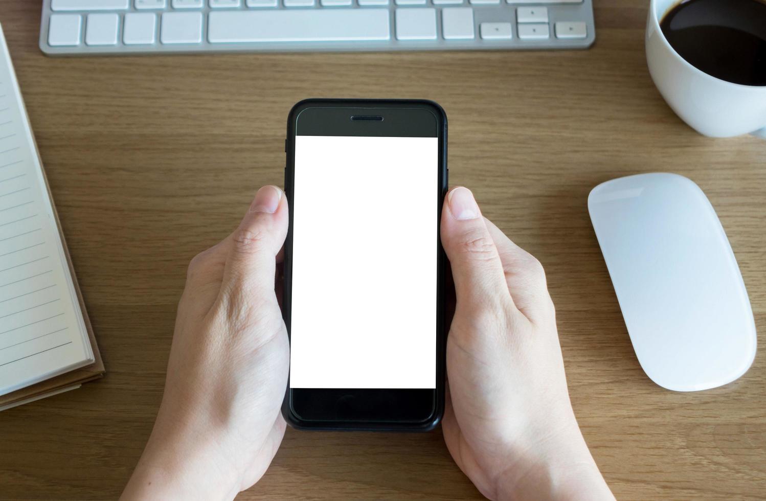 woman hands holding empty screen of smartphone on wood desk work photo