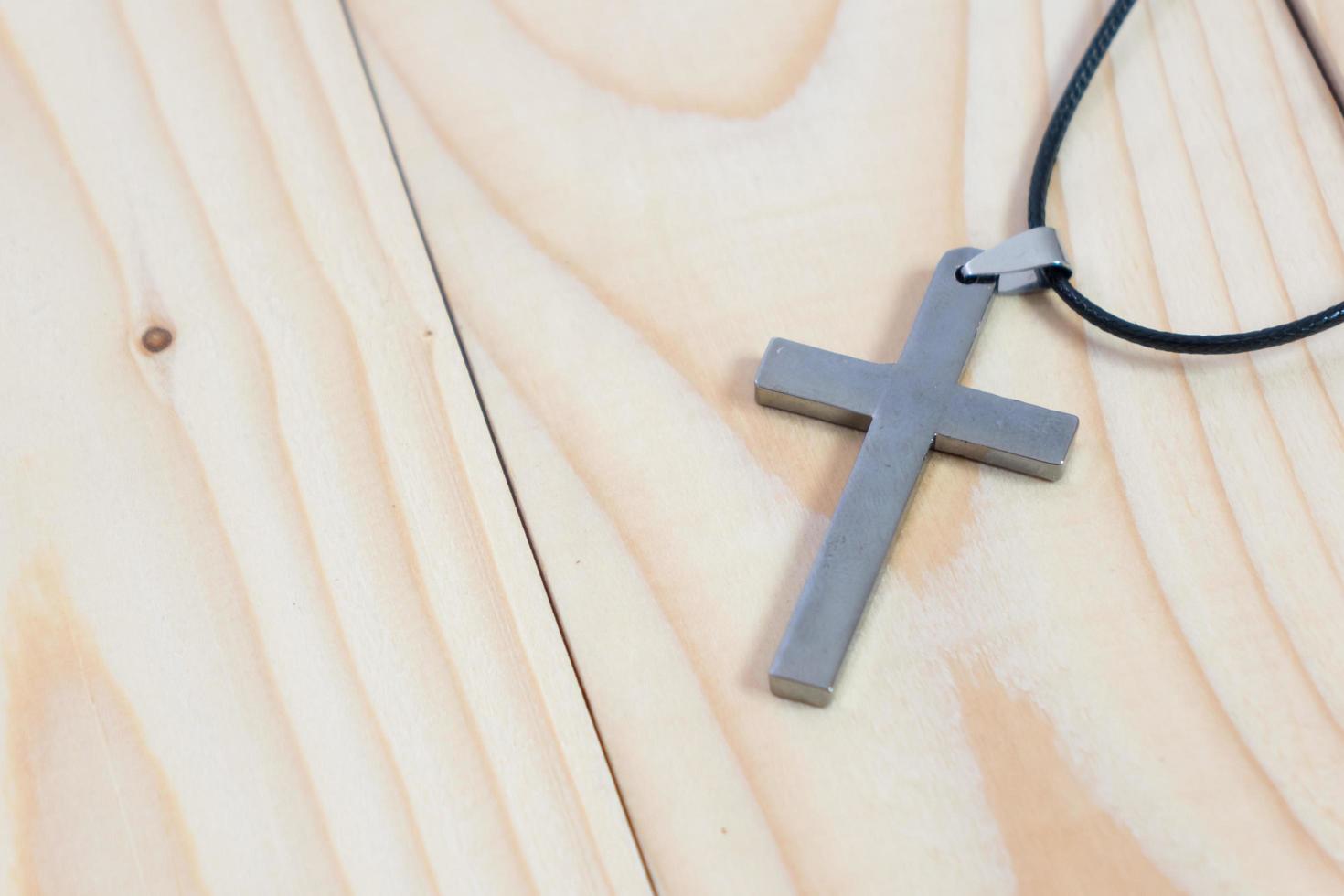 Necklace with silver cross on wooden table photo