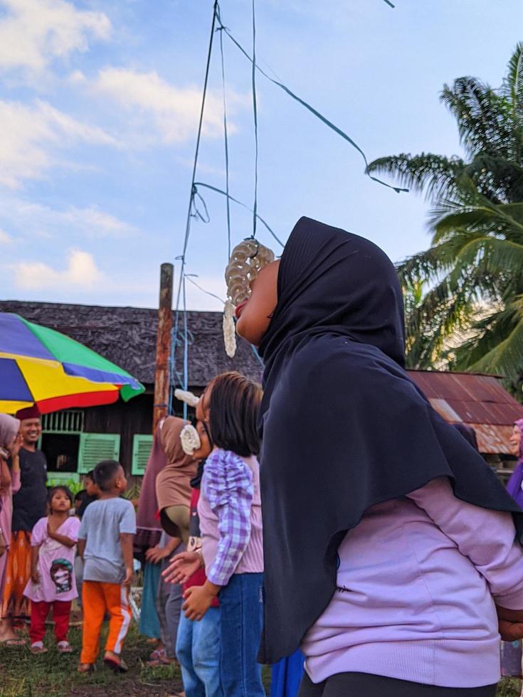 the excitement of adults and children taking part in a cracker eating competition to enliven the independence day of the republic of Indonesia, East Kalimantan, Indonesia August 13, 2022 photo