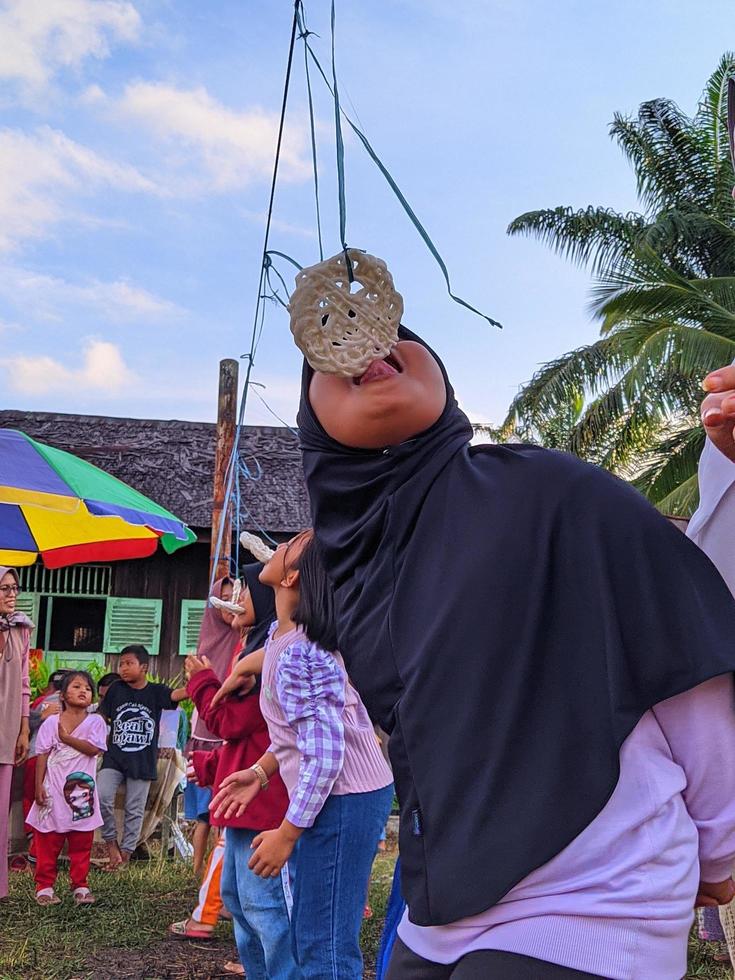 la emoción de adultos y niños que participan en una competencia de comer galletas para animar el día de la independencia de la república de indonesia, kalimantan oriental, indonesia, 13 de agosto de 2022 foto