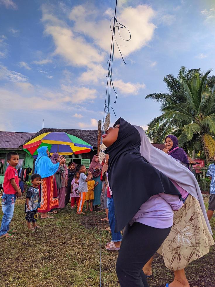 the excitement of adults and children taking part in a cracker eating competition to enliven the independence day of the republic of Indonesia, East Kalimantan, Indonesia August 13, 2022 photo