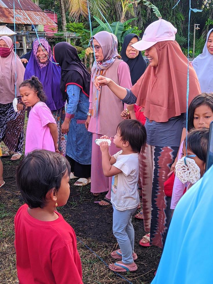 the excitement of adults and children taking part in a cracker eating competition to enliven the independence day of the republic of Indonesia, East Kalimantan, Indonesia August 13, 2022 photo