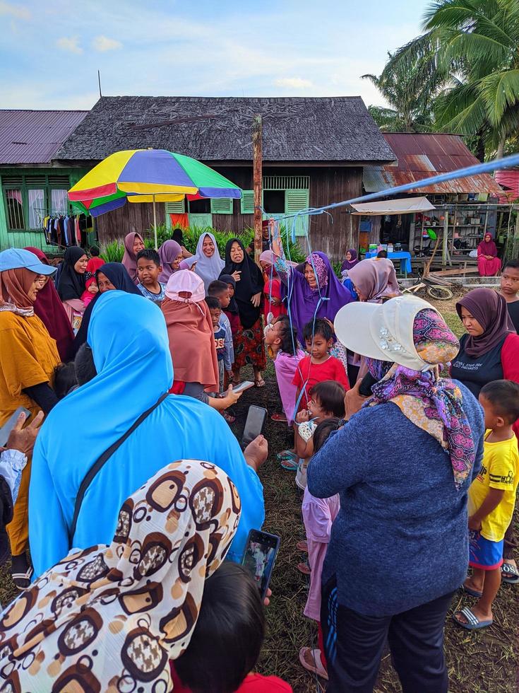 the excitement of adults and children taking part in a cracker eating competition to enliven the independence day of the republic of Indonesia, East Kalimantan, Indonesia August 13, 2022 photo