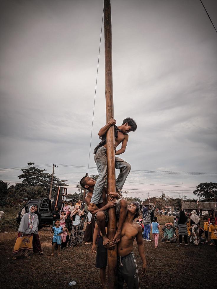 the excitement of children and adults taking part in the areca climbing competition to enliven the independence day of the republic of Indonesia, east kalimantan, indonesia, august, 14,2022 photo