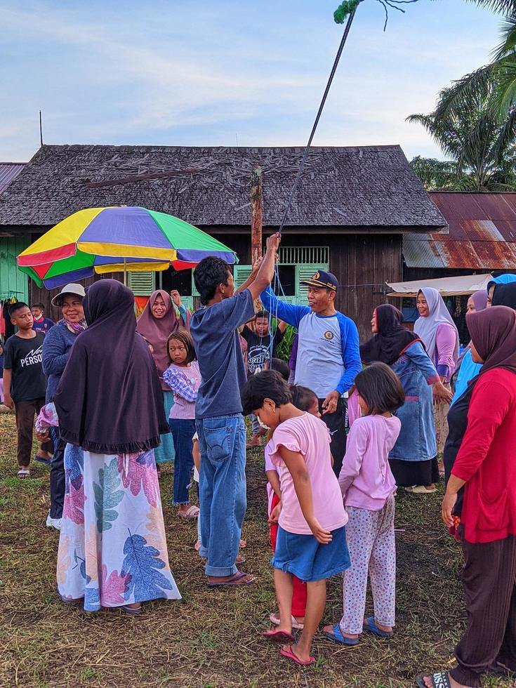 the excitement of adults and children taking part in a cracker eating competition to enliven the independence day of the republic of Indonesia, East Kalimantan, Indonesia August 13, 2022 photo
