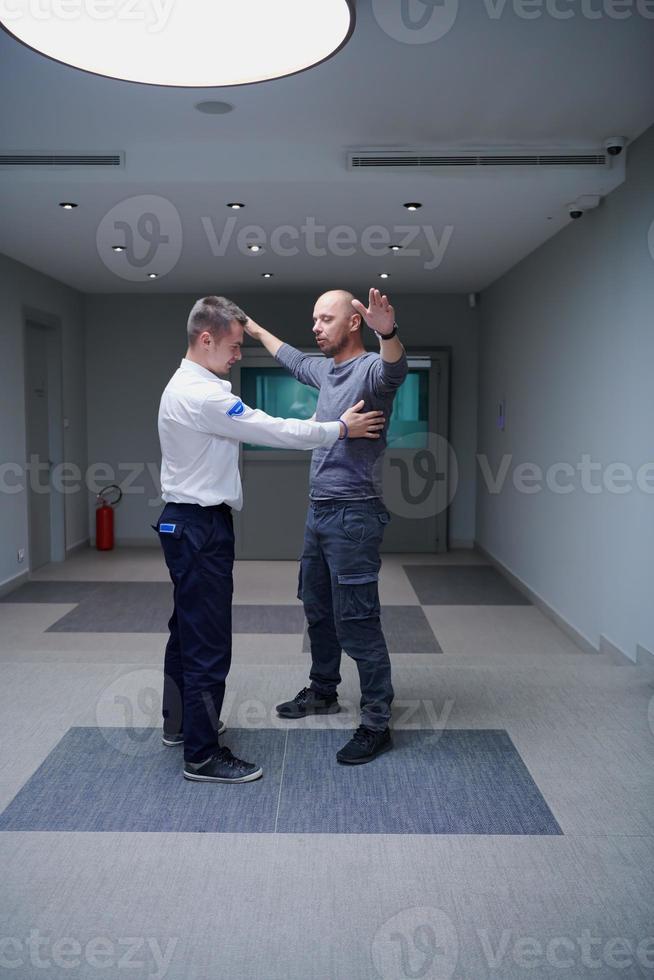 Security guard making body searching procedure on man photo