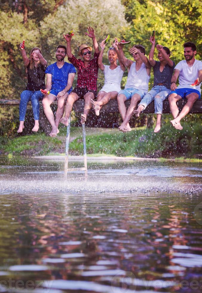 amigos disfrutando de la sandía mientras están sentados en el puente de madera foto