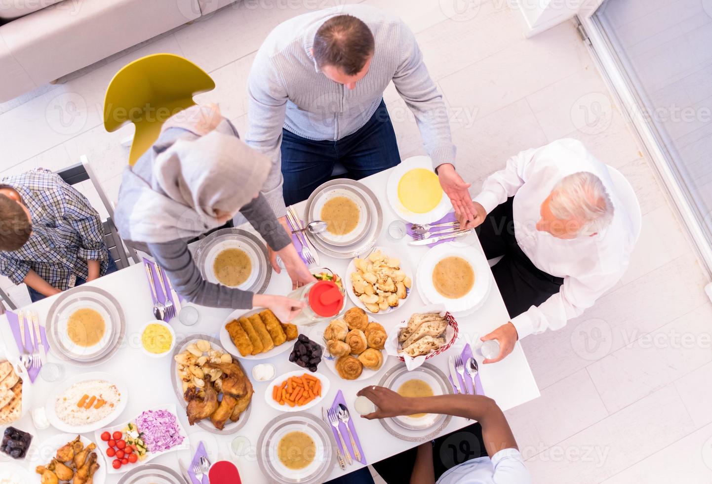 vista superior de la familia musulmana multiétnica moderna esperando el comienzo de la cena iftar foto