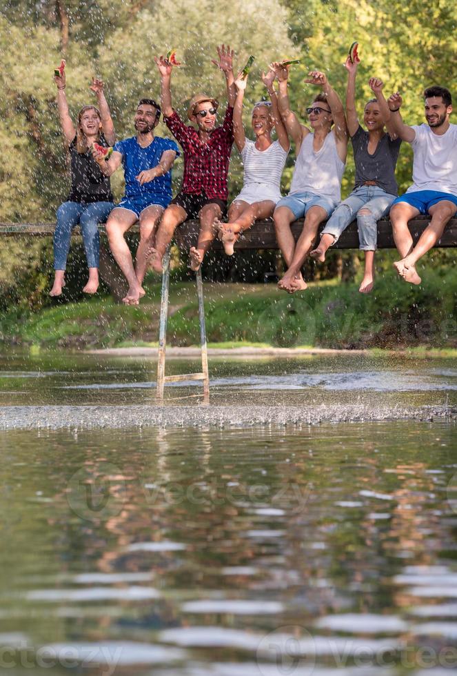 amigos disfrutando de la sandía mientras están sentados en el puente de madera foto