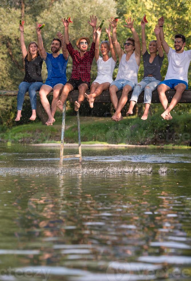 amigos disfrutando de la sandía mientras están sentados en el puente de madera foto