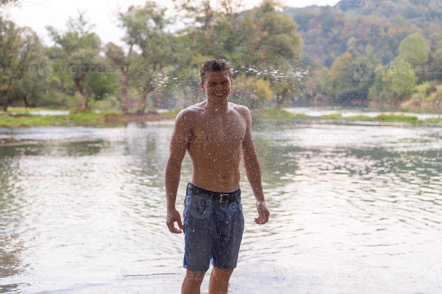 man with a bare torso splashing water photo