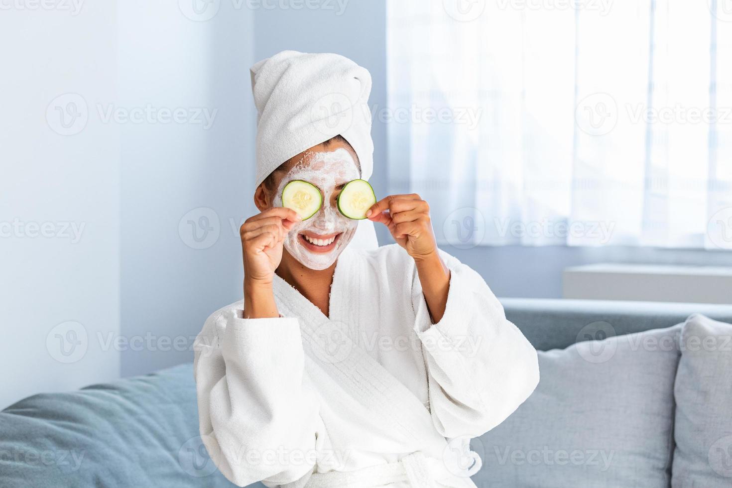 Woman with facial mask and cucumber slices in her hands. Beautiful young woman with facial mask on her face holding slices of fresh cucumber. Young woman with clay facial mask holding cucumber slices photo
