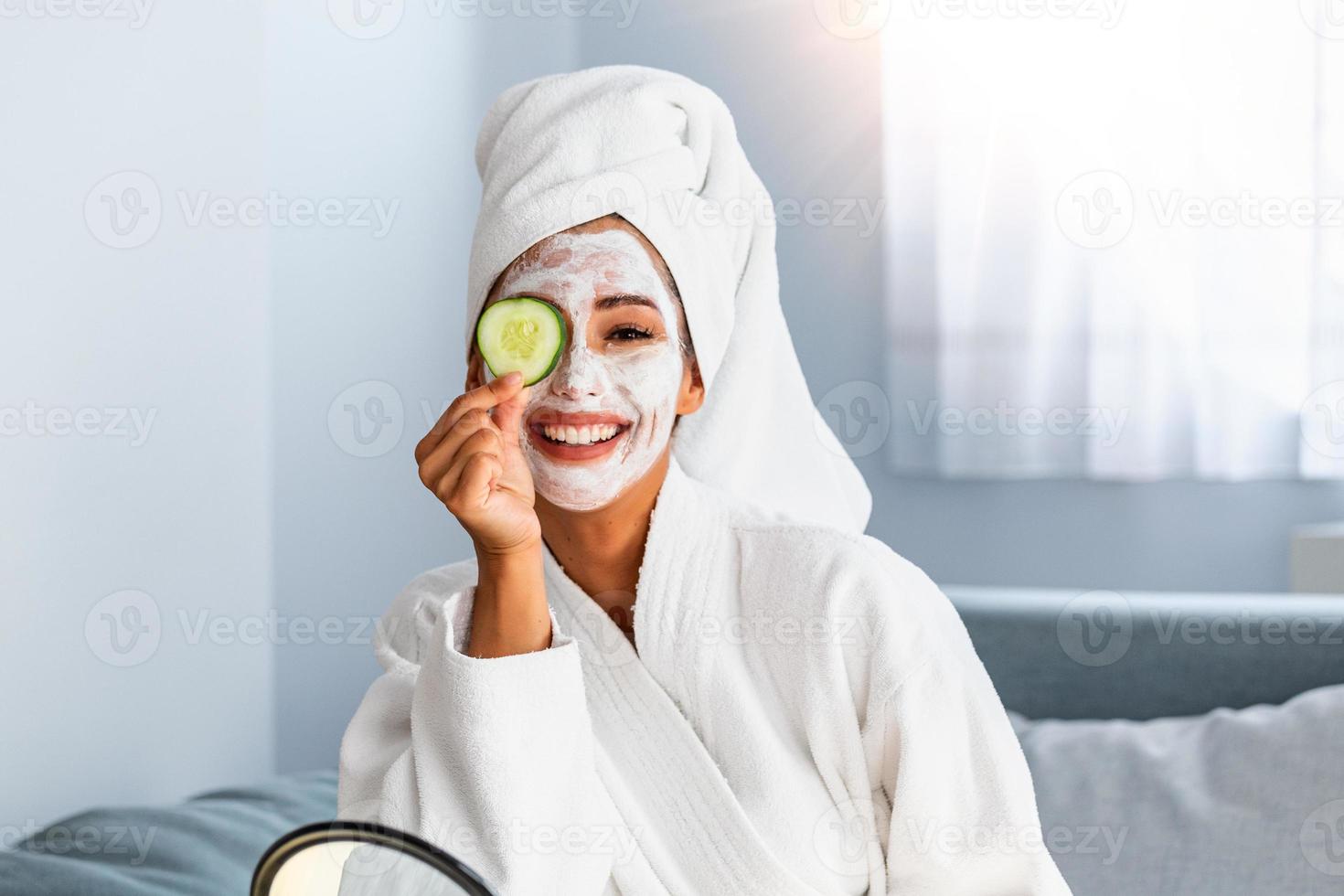 Young woman with cleansing mask on her face at home. Skin care. Woman aplying beauty mask,close up. So beautiful. Close-up of girl with beauty mask on her face looking in mirror. photo