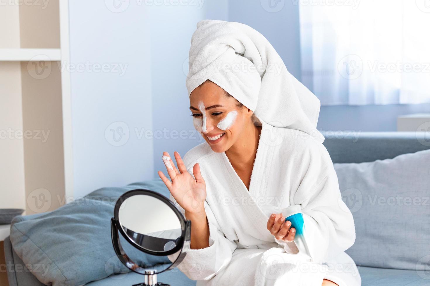 So beautiful. Close-up of girl with beauty mask on her face looking in mirror. Girl uses natural mask. Attractive young woman sitting with a facial mask on her skin photo