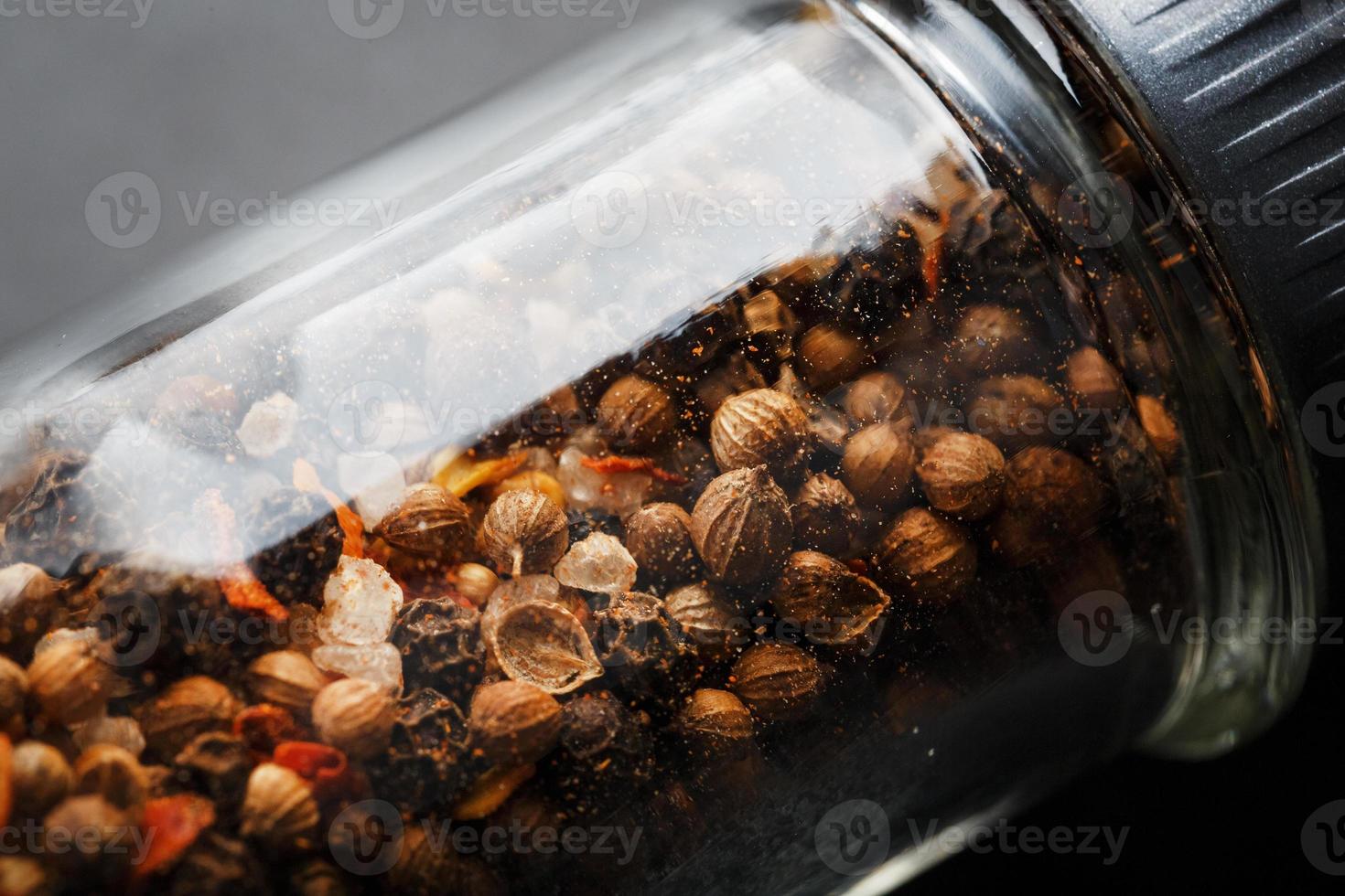 A mixture of seasonings, spices and herbs in a glass mill Close-up. photo