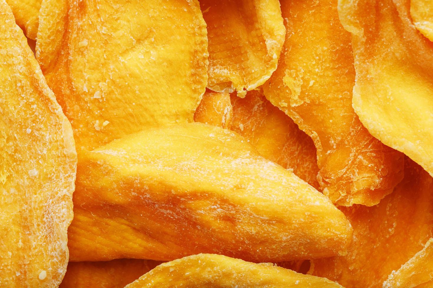 Pieces of sweet dried mango close-up as a background in full screen photo