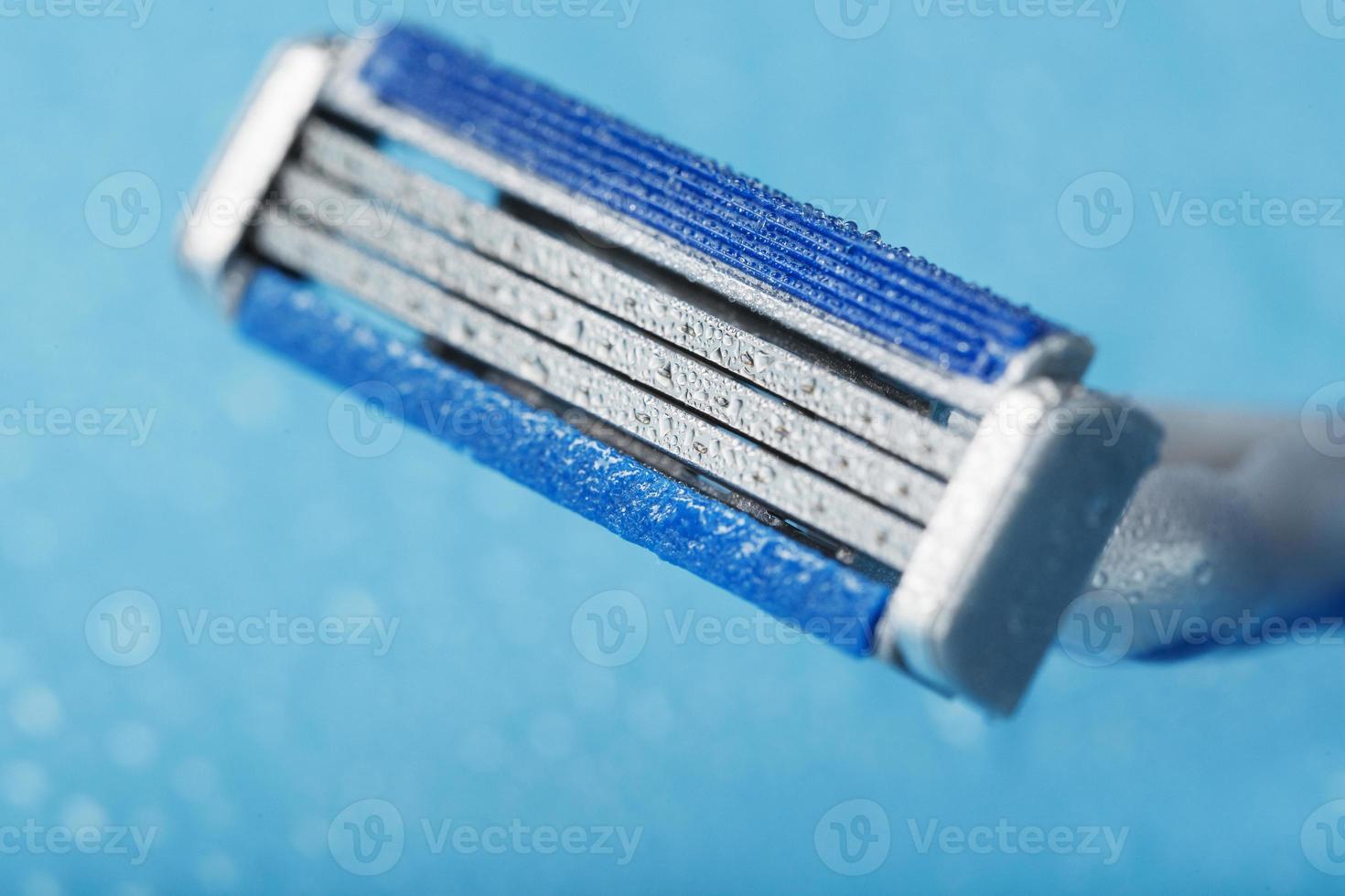 Shaving machine with three blades on a blue background with water drops in close-up photo