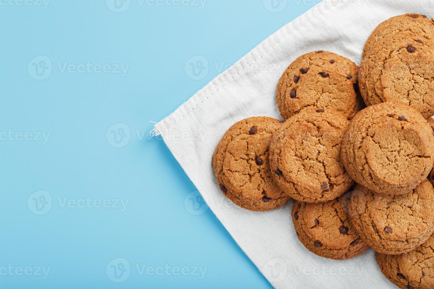 A bunch of oatmeal cookies with chocolate on a napkin on a blue background photo