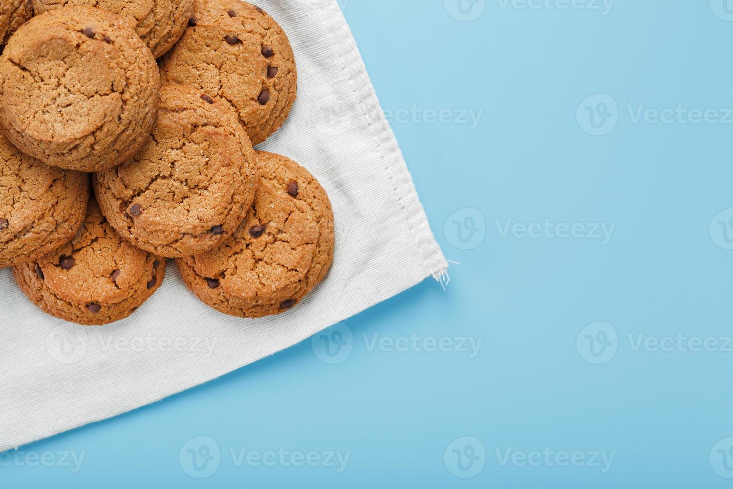 A bunch of oatmeal cookies with chocolate on a napkin on a blue background photo