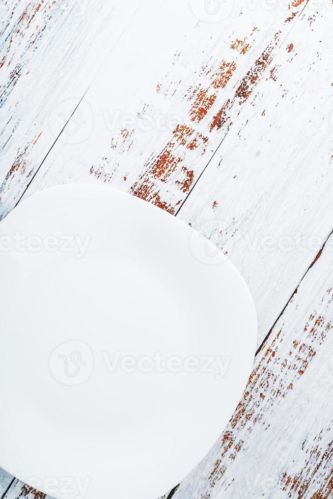 An empty round white plate on a blue wooden table. photo