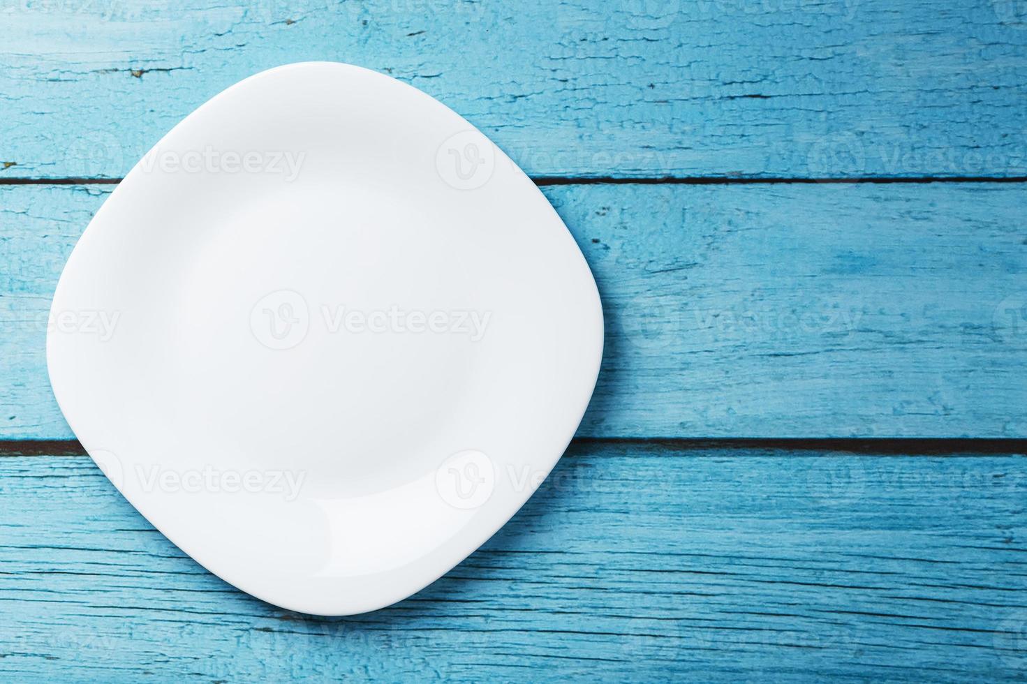 Empty round bowl on a blue wooden background from above. Free space photo