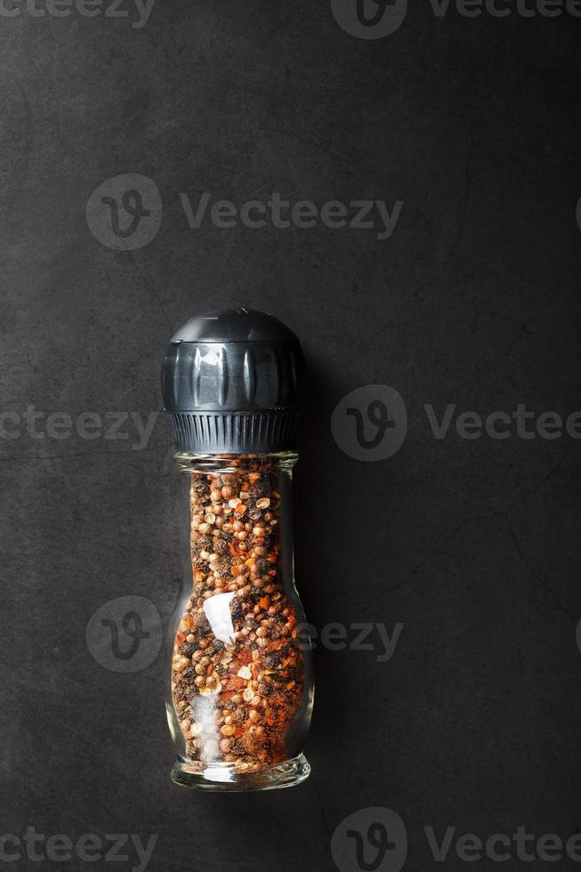 A mixture of seasonings, spices and herbs in a glass mill on a black background. photo