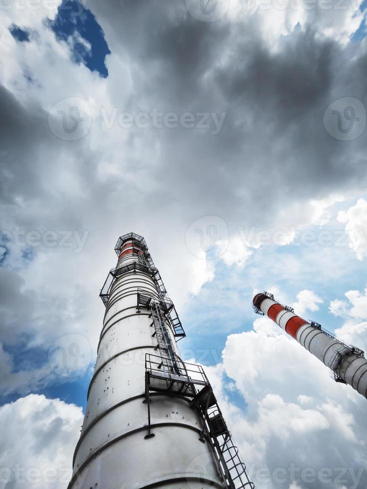 White chimneys of a power plant on a background of clouds with diagonal lines photo