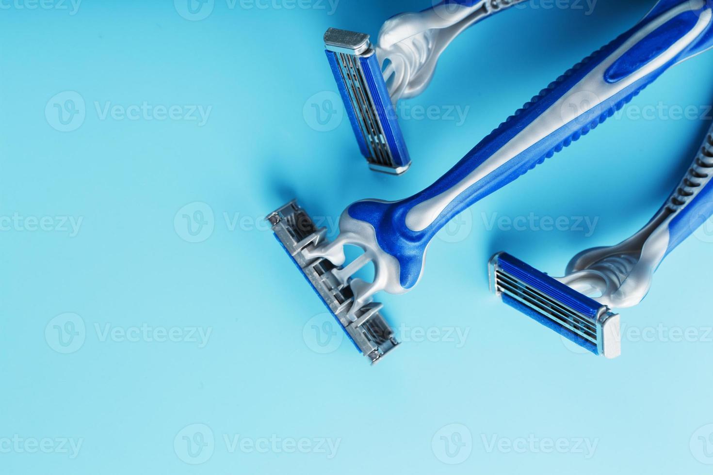 máquinas de afeitar azules en una fila sobre un fondo azul con cubitos de hielo foto