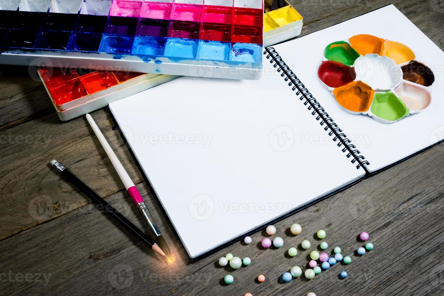 closeup open note book with tray colors on wood background photo