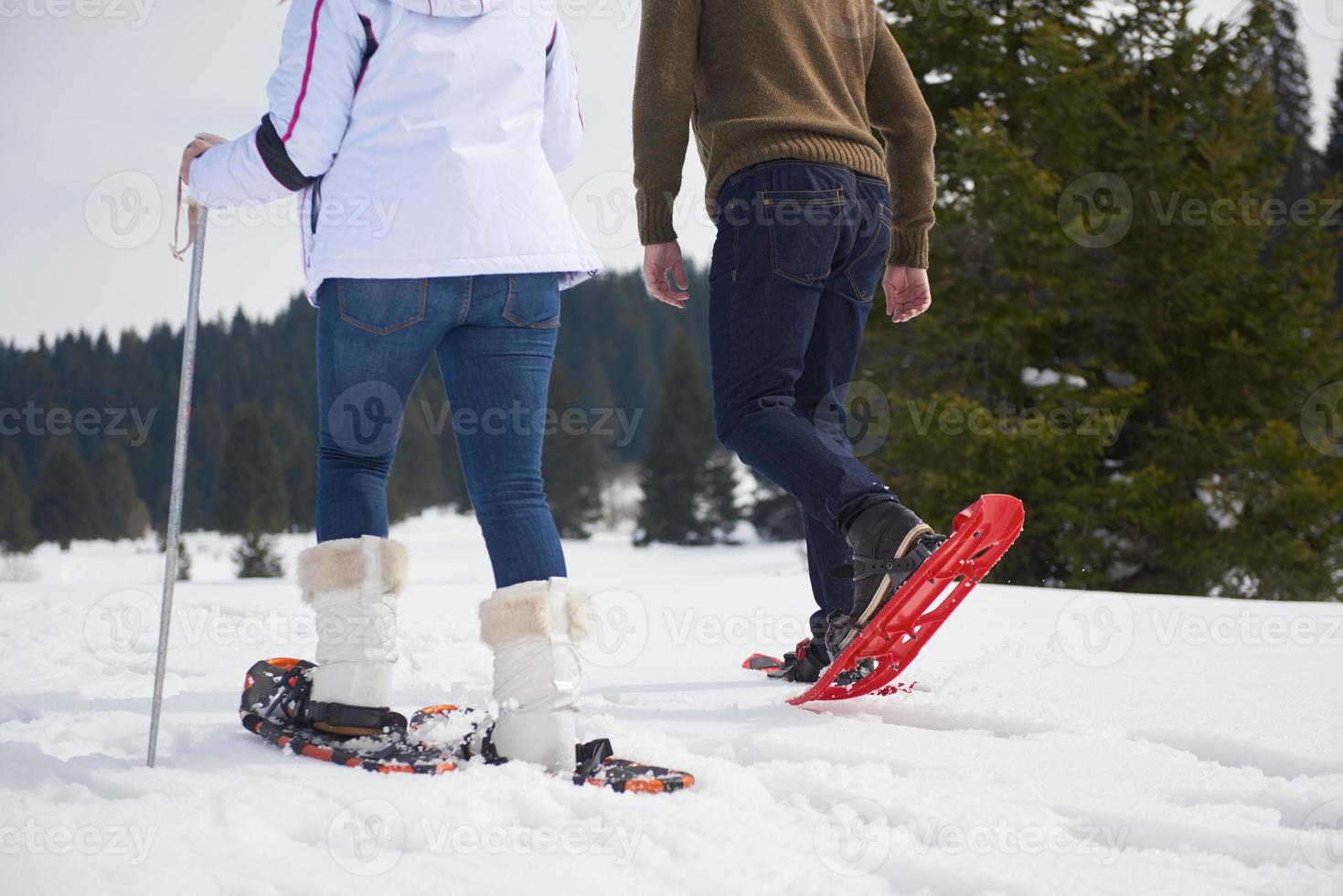 pareja divirtiéndose y caminando con raquetas de nieve foto