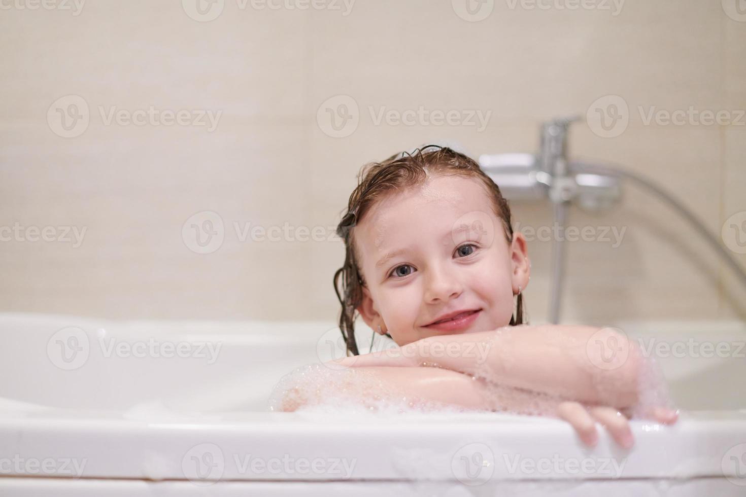 little girl in bath playing with soap foam photo