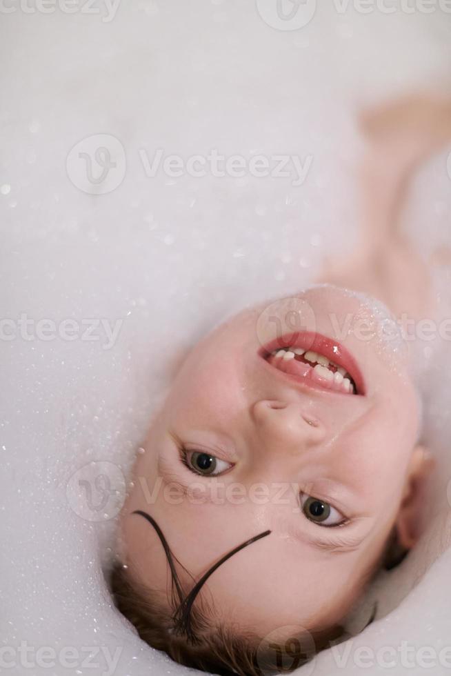 little girl in bath playing with soap foam photo